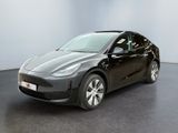 une Tesla Model Y noire garée dans une pièce aux murs blancs