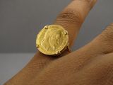 quelqu'un tient une bague sur laquelle est posée une pièce d'or