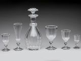 six wine glasses and a decanter on a table