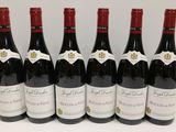 six bottles of red wine are lined up on a table