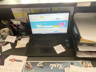 a laptop computer sitting on top of a desk covered in papers
