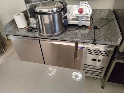 un plan de travail en acier inoxydable dans une cuisine professionnelle, sur lequel est posé un mixeur