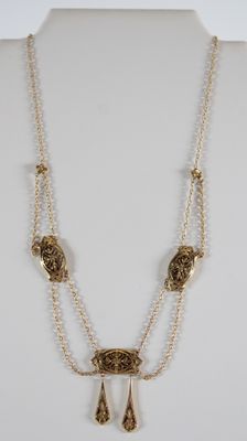 un collier en or composé d'une longue chaîne et de deux perles pendantes