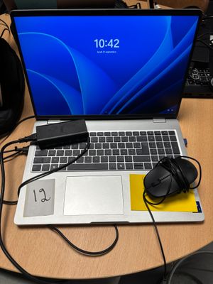 un ordinateur portable posé sur un bureau, avec une souris et un casque
