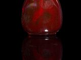a red vase sitting on a black surface with a black background