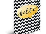 a black and white chevroned notebook with a gold hello balloon on it