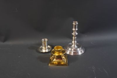 two silver candlesticks and a glass candle holder on a table