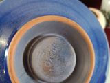 a close up of a blue and orange vase on a table