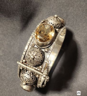 a close up of a silver bracelet with a citrine stone on it