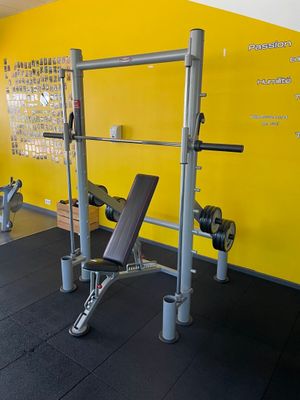 une salle de sport équipée d'un banc, d'haltères et d'autres appareils