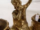 une statue en or représentant une femme assise sur un vase