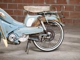 an old blue motorcycle parked in front of a brick wall
