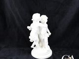 une statue blanche représentant un garçon et une fille se tenant la main sur un fond noir