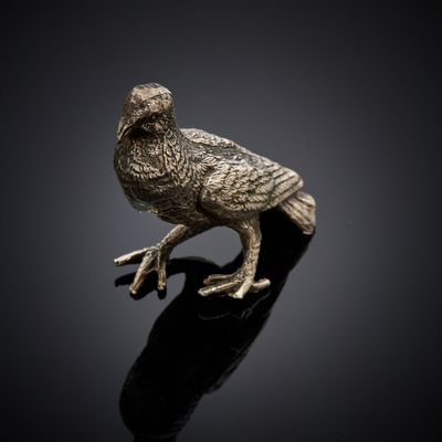 a silver bird figurine sitting on top of a black surface