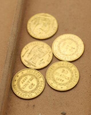 quatre pièces d'or posées sur une table, à côté d'un couteau
