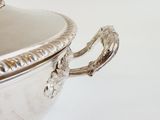 a large silver bowl with handles on a white table