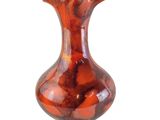 un vase rouge posé sur une surface blanche