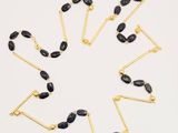 a close up of a necklace with black stones on a white surface