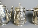 three silver teapots are lined up in a row on a table