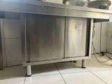 une table en acier inoxydable sur laquelle sont posés des casseroles et des poêles