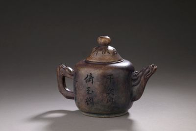 a brown teapot with writing on it sitting on a table