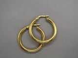 two pairs of gold hoop earrings on a gray surface