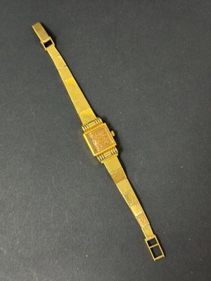 a close up of a gold watch on a black surface