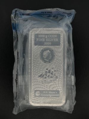 un gros plan d'un lingot d'argent emballé dans du plastique, posé sur une surface noire