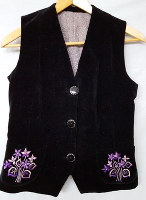 black velvet vest with purple flowers on it and a wooden hanger on a white background