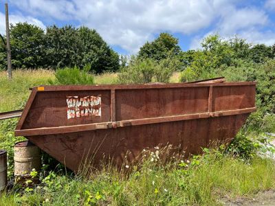 a rusted dumpster sitting on the side of the road