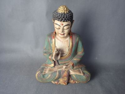 statue d'un Bouddha assis en position de méditation sur un fond gris