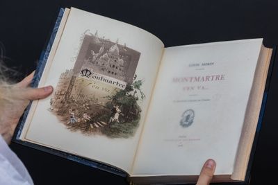 une personne tenant un livre ouvert sur lequel figure l'image d'un château