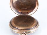 an antique pocket watch sitting on a white surface with a key