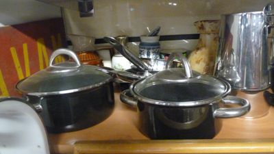 des casseroles et des poêles posées sur un plan de travail en bois dans une cuisine