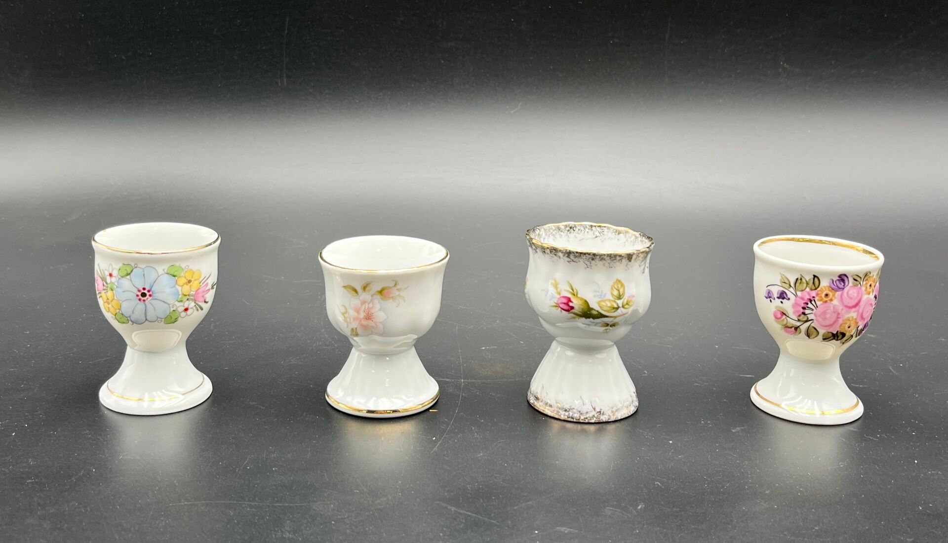 POLOGNE ( Rece mal D. Szymariska, Chodziez). Ensemble de quatre coquetiers en porcelaine et en faïence à fond blanc e...
