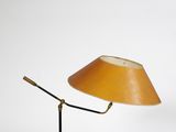 une lampe jaune posée sur un pied noir, avec un fond blanc