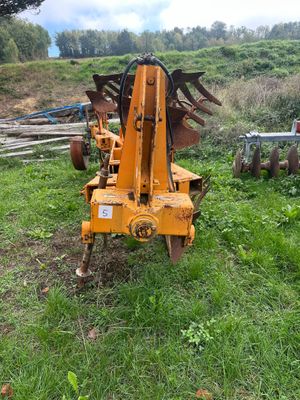 a tractor with a plow attached to it in the grass