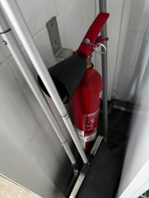 un extincteur rouge dans un coin de la salle de bains