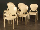 four white plastic chairs sitting in a row against a black wall