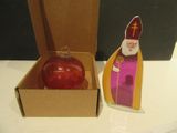 une décoration rouge dans une boîte en carton, à côté d'une autre décoration rouge