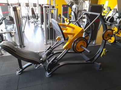 des appareils de musculation jaunes et noirs dans une salle de sport au sol noir