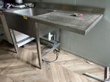 a stainless steel sink and a metal table in a kitchen