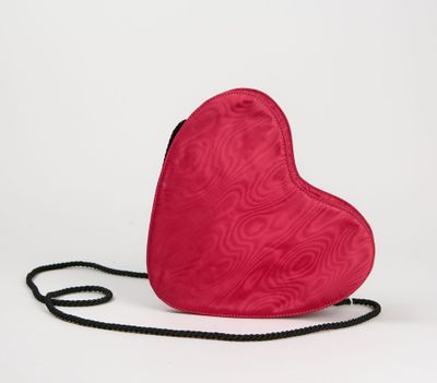 un sac à main rouge en forme de cœur posé sur une surface blanche