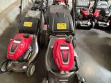 Trois tondeuses à gazon sont alignées les unes à côté des autres dans un garage