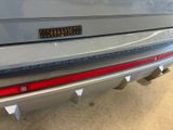 the rear end of a silver car with a sticker on it