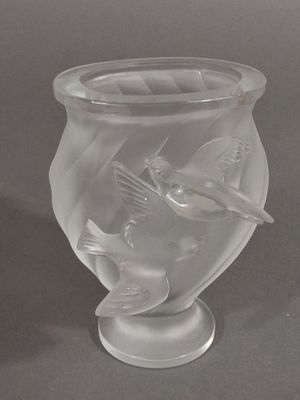 a glass vase with a bird on it on a table