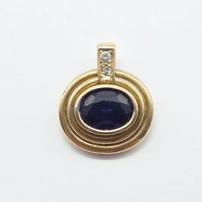 un gros plan d'un pendentif en pierre bleue et diamants posé sur une surface blanche