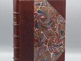 un livre marron dont la couverture marbrée se détache sur un fond blanc