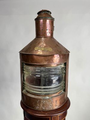 un grand luminaire en cuivre posé sur un socle en bois