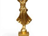 gold statue of a woman holding a bird on a pedestal